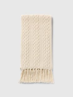 a white knitted blanket with fringes