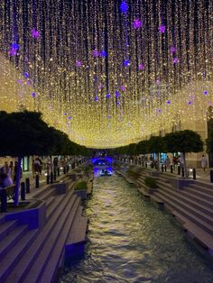 people are standing in the middle of a river under lights and chandeliers hanging from the ceiling