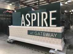 a sign that says aspire at gateway in the middle of a warehouse floor with other signs behind it