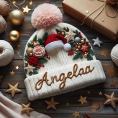 a knitted hat with the word angella written on it surrounded by christmas decorations