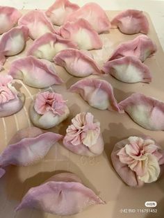 some pink and white flowers are laying on a sheet of waxing paper with other things in the background