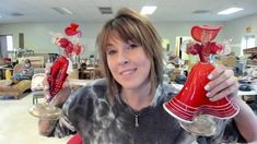 a woman holding two red vases with hearts on them in an office setting,