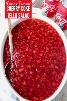 a white bowl filled with cranberry sauce next to two cans of soda and a spoon