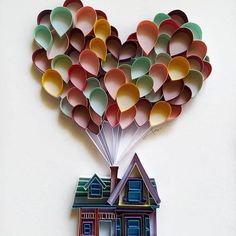 a house shaped like a bunch of balloons floating in the air over a white wall