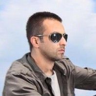 a man wearing sunglasses sitting on top of a motor scooter in front of a blue sky