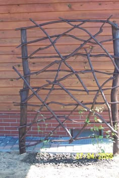 a wooden fence made out of branches next to a brick wall