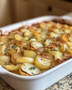 a casserole dish with potatoes and herbs in it sitting on a counter top