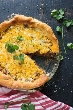 a cheesy quiche pie on a plate with a slice missing from it