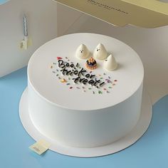 there is a white cake with sprinkles and two small birds on top