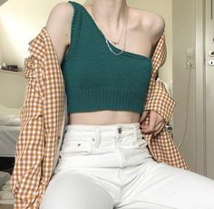 a woman wearing white pants and a green crop top is posing for the camera with her hands on her hips