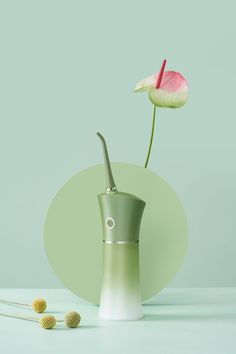 a single flower in a vase on a table with other items around it, including needles and thread