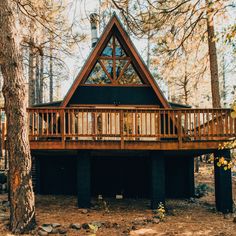 a house in the woods with a deck and stairs leading up to it's roof