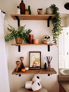 a bathroom with two shelves above the toilet and various items on the shelf below it