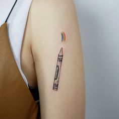 a woman with a tattoo on her arm has a pencil in the shape of a rainbow