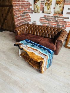 a brown leather couch sitting on top of a hard wood floor next to a brick wall