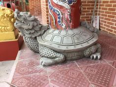 a statue of a turtle sitting on top of a red and white tile floor next to a brick wall