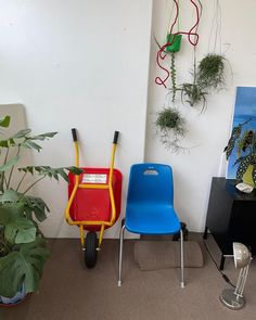 two children's chairs and a wheelbarrow with plants on the wall