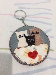 a keychain with three cats on it sitting on top of a tablecloth