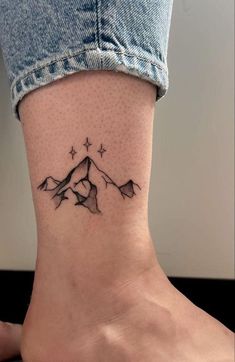 a woman's foot with a small mountain tattoo on the side of her ankle