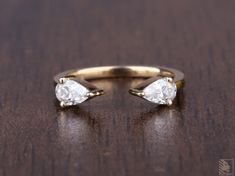 two pear shaped diamond rings sitting on top of a wooden table