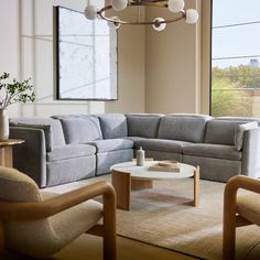 a living room filled with furniture next to a large window and a painting on the wall