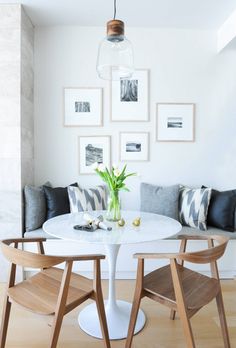 a white table with some chairs around it and pictures on the wall behind it,