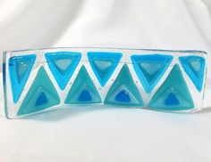 a blue and white glass object on a white tableclothed background, with triangles in the center