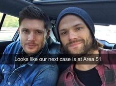 two men sitting in the back seat of a car, one is wearing a beanie