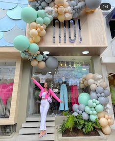 a woman standing in front of a building with balloons on the outside and behind her