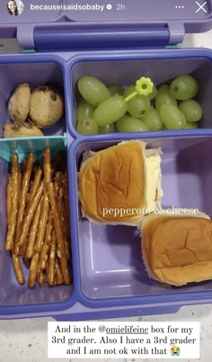 a lunch box with grapes, pretzels, and bread in it is shown