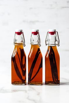 three glass bottles filled with liquid sitting on top of a white counter next to each other