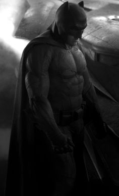 the dark knight batman standing in front of an airplane with his hands on his hips