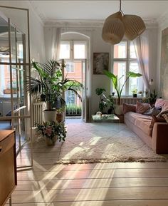 a living room filled with lots of furniture and plants on the wall next to windows