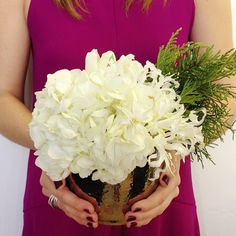 a woman in a pink dress holding a vase with white flowers