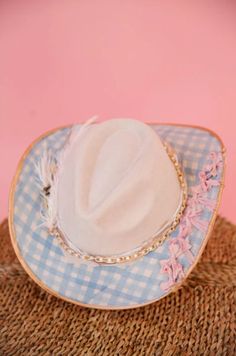 Introducing THE AUDRA RANCHER HAT - a playful twist on the classic cream rancher hat. This unique hat features gold accents and a stylish blue gingham pattern. With a gold chain band and pink bows, it's the perfect mix of chic and quirky. Plus, the white feather combo adds a touch of whimsy. Get ready to turn heads and stand out from the crowd! Rancher Hat, Unique Hats, Pink Bows, Gingham Pattern, White Feather, White Feathers, Blue Gingham, Spring 2024, Pink Bow