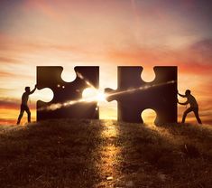 two people holding puzzle pieces with the sun setting behind them