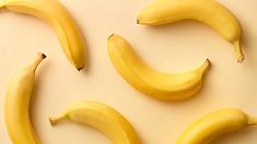 four bananas arranged in the shape of a smiley face on a white surface with yellow background