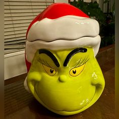 the grin face has been painted on this green planter, and is wearing a santa hat