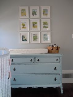 a baby's room with a dresser, crib and pictures on the wall