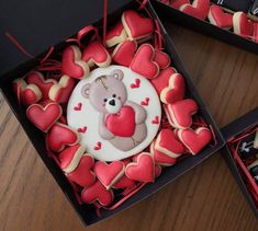 two boxes filled with heart shaped cookies and a teddy bear on the top one is decorated