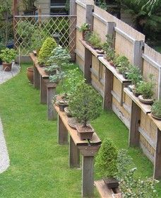 a long row of planters on the side of a fenced in garden area