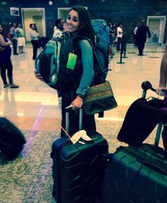 a woman is standing with her luggage at the airport