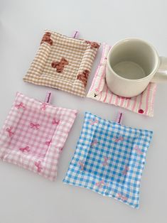 four different colored squares on a table with a coffee mug and napkins next to them