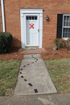 a brick building with a white door and red cross painted on the sidewalk next to it