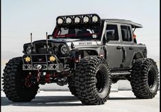 a large gray truck with four wheels and lights on it's flatbed in the desert