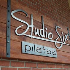 the sign for studio six pilates is mounted on a brick wall