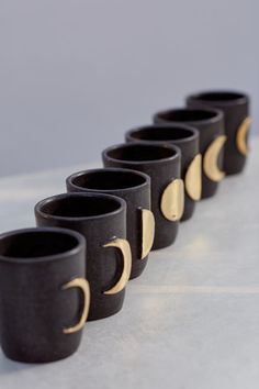 black cups with gold crescent and moon designs lined up in a row on a table