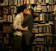 two people kissing each other in front of a bookshelf