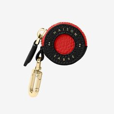 a red and black keychain with the name maison sabre on it's side