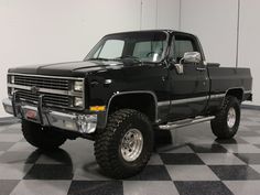 a black pickup truck parked on top of a checkered floor